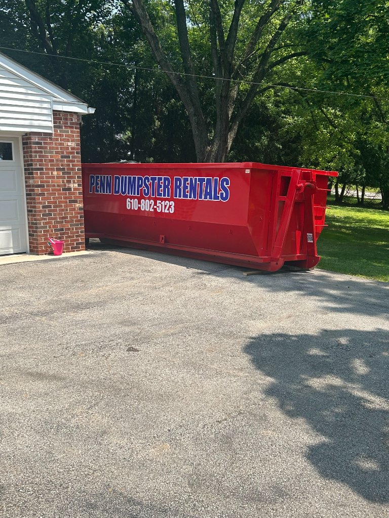 Dumpster in a driveway next to a garage